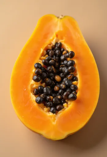 Свежа, нарязана папая върху дървена повърхност с черни семена